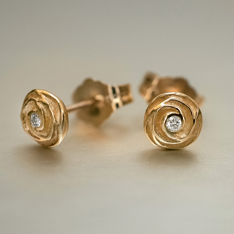 Hand carved rose flower stud earrings with small gypsy set diamonds in the center of the flowers, cast in 14K yellow gold.
