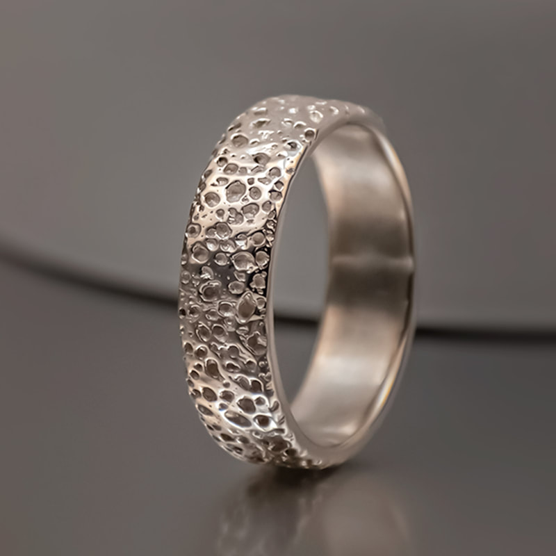Men's platinum rugged wedding ring with organic structure resembling a porous rock surface.