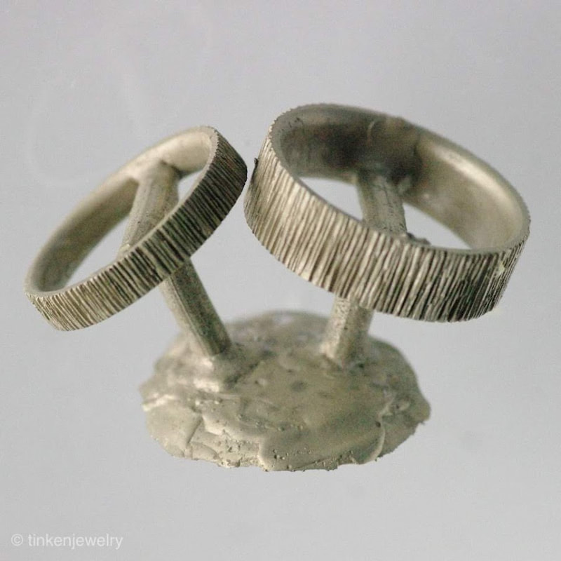 Raw Casting of White Gold Matching Wedding Bands with Casting Button still attached. The rings have a deep, vertical lined texture on the surface.