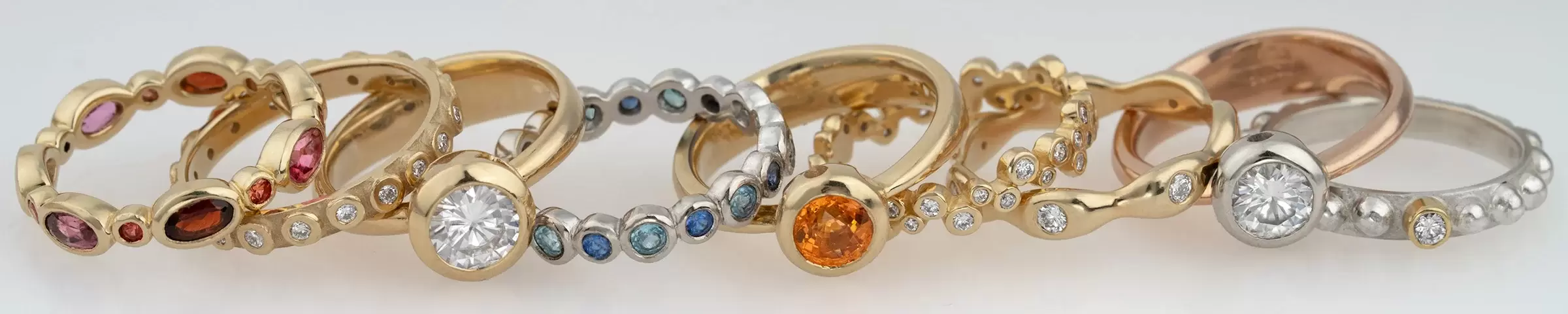 collection of bezel set gold rings featuring diamonds and precious gemstones, custom handcrafted by Tinken Jewelry